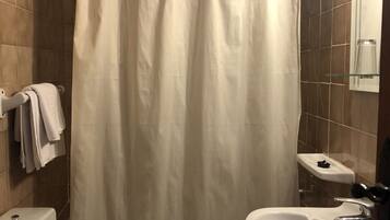 Un baño con inodoro, lavamanos y cortina de ducha.