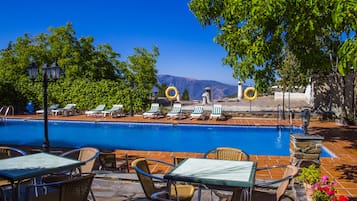 Una piscina al aire libre de temporada, sillones reclinables de piscina