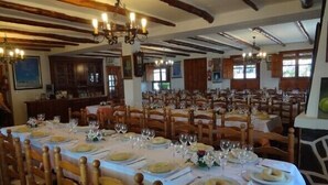 A large dining hall with wooden chairs and tables set for a meal. - Hostal Poqueira (Capileira)