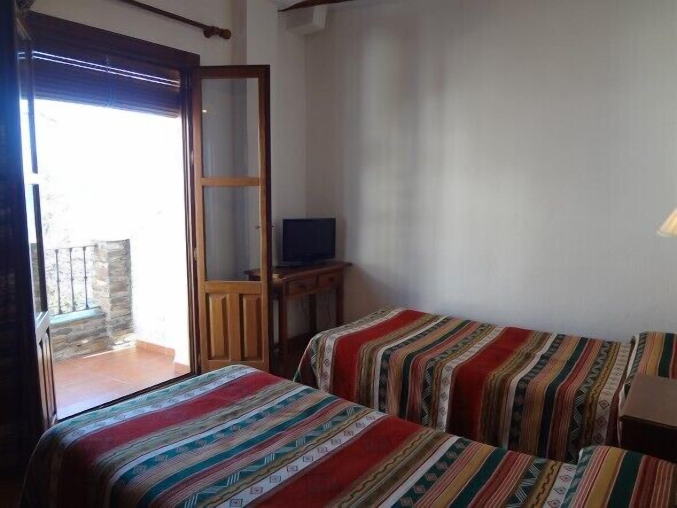 A room with two beds, a TV, and a balcony.