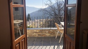 A balcony with a stone wall, a metal railing, and a view of mountains. - Hostal Poqueira (Capileira)