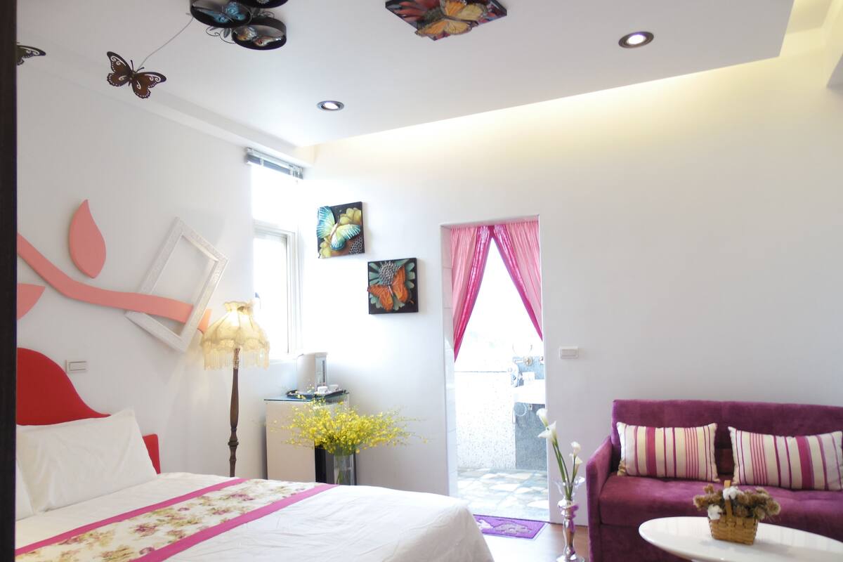A bedroom with a bed, a sofa, a table, and artwork on the walls.