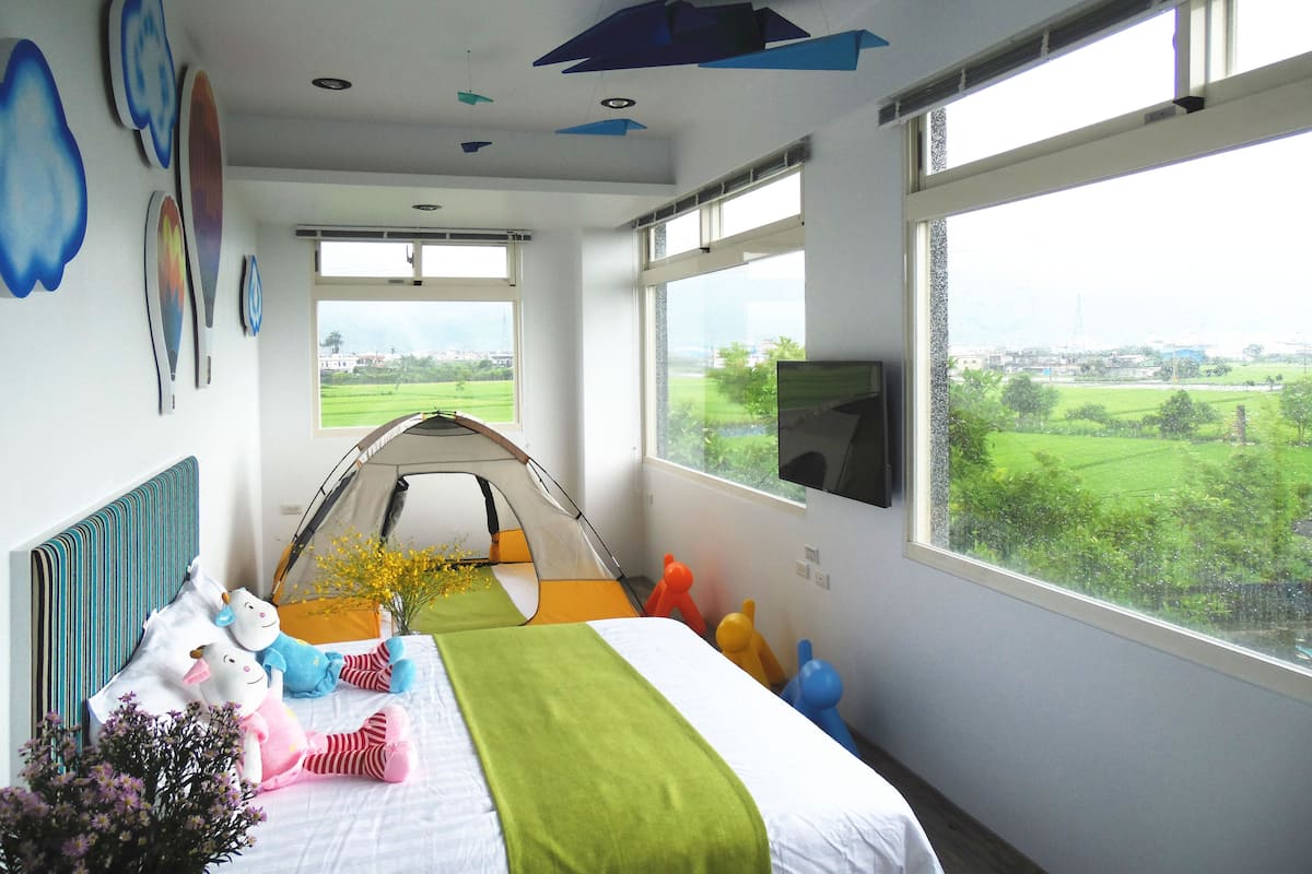 A bedroom with a bed, a tent, and a TV.
