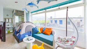 Una habitación con una tienda de campaña, un sillón colgante y un sofá con cojines de colores.