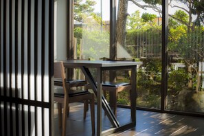 Un interior moderno con una mesa y sillas de madera, ventanas amplias que ofrecen vistas a zonas verdes y una valla de madera en el exterior.