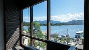 A room with large windows overlooking a lake, a dock with boats, and a mountainous landscape. - Shinpuro (Miyazu)