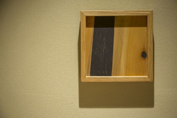 A framed picture with a wooden frame and a dark panel in the center, mounted on a textured wall. - Shinpuro (Miyazu)