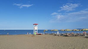 Une plage avec une tour de surveillance, des parasols et des chaises de plage.