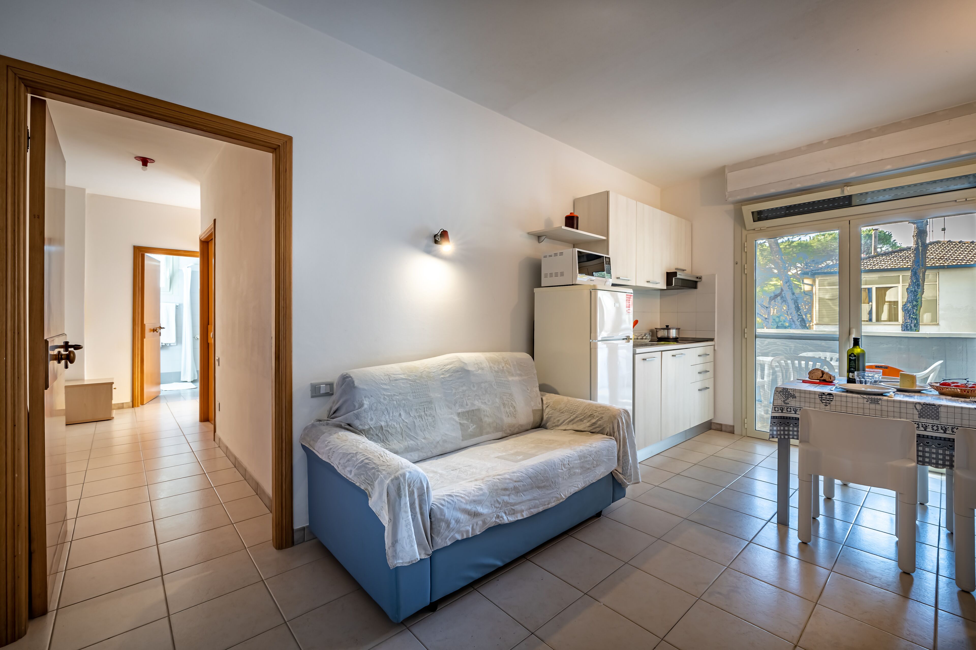 Un espacio habitable compacto con kitchenette, un sofá y una zona de comedor.