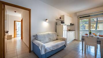 Un espacio habitable compacto con kitchenette, un sofá y una zona de comedor.