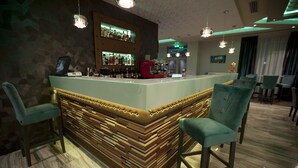 Zona de bar con mostrador, taburetes y paneles de madera.