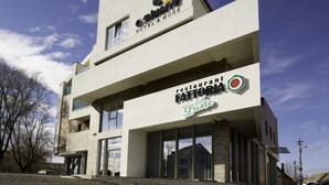 Un edificio moderno con un letrero que dice 'Exclusive Hotel & More' y 'Restaurant Fattoria del Gusto'.