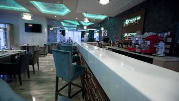 A modern bar area with a long counter, bar stools, and a variety of bar equipment.