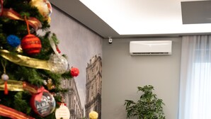 Un moderno vestíbulo de hotel con un árbol de Navidad, sillas amarillas y un amplio ventanal con cortinas.