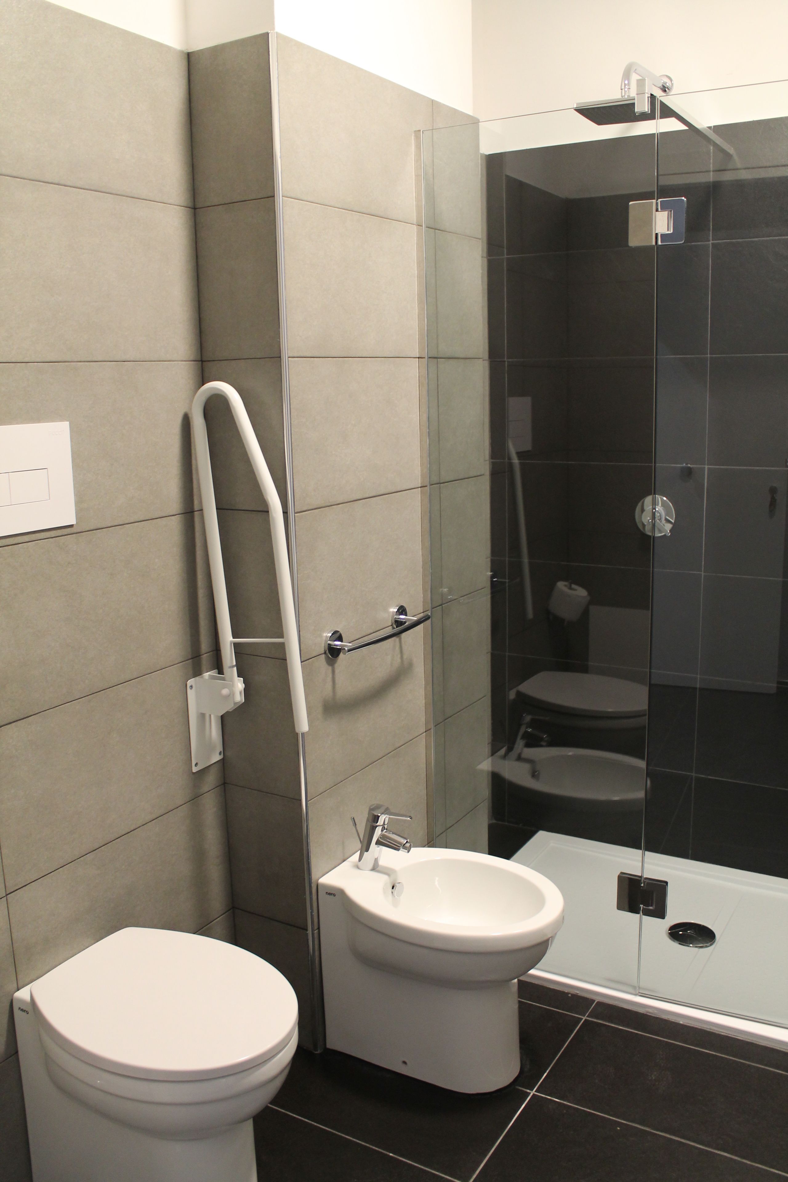 A modern bathroom with a toilet, bidet, and glass-enclosed shower.