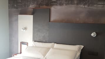 Habitación de hotel con una cama grande, una mesita de noche, una lámpara de pared y un mural de un edificio.