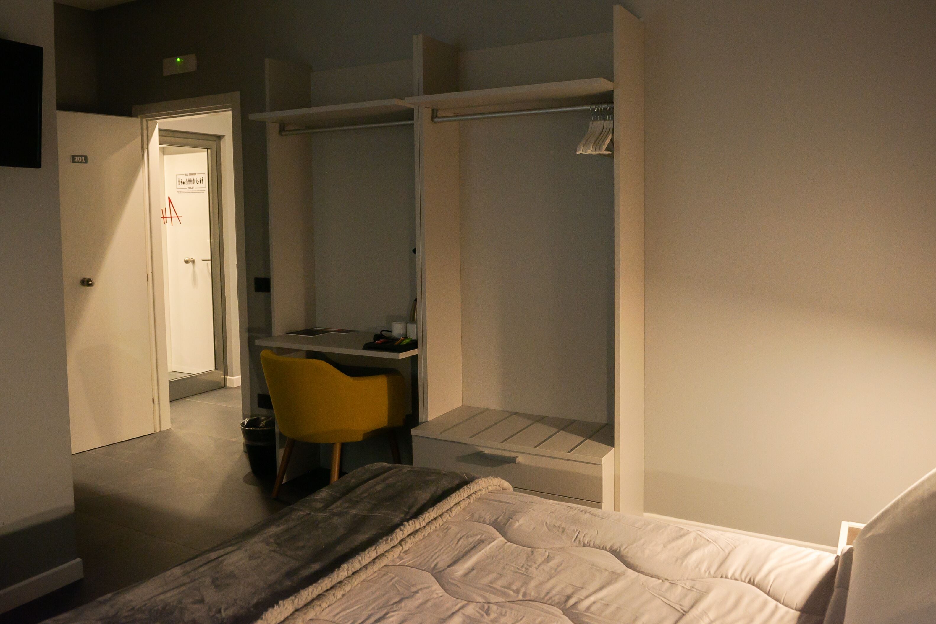 Een slaapkamer met een bed, een bureau, een stoel en een kledingkast.