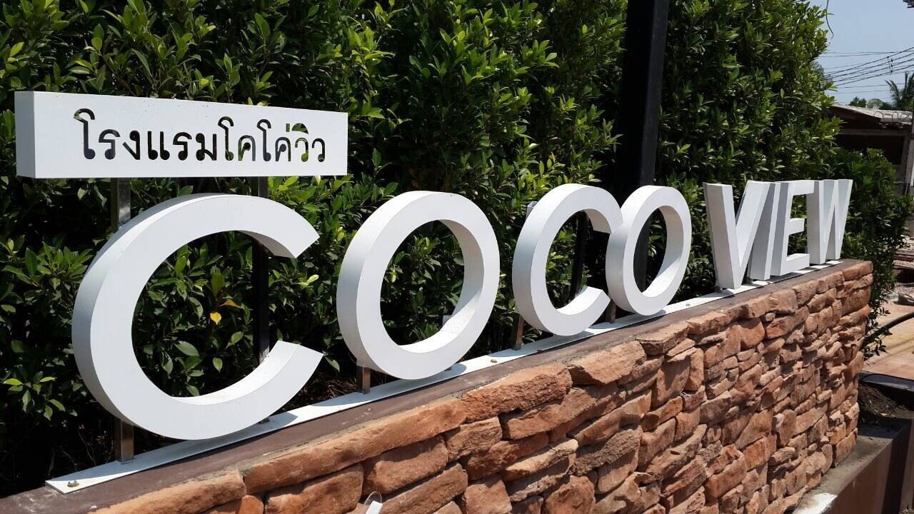 Um sinal com a palavra 'CocoVe' e escrita tailandesa, indicando um local ou estabelecimento.