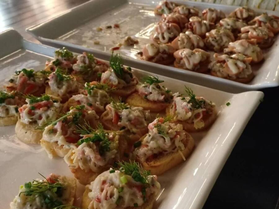Un bufé con aperitivos de mariscos, incluyendo pan con camarones y otros platos.