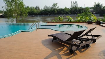 Una piscina al aire libre, sillones reclinables de piscina