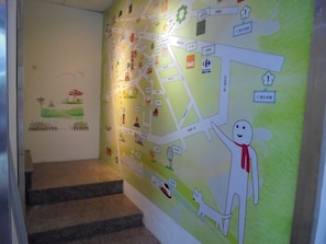 A wall with a map and a cartoon character pointing to a location.