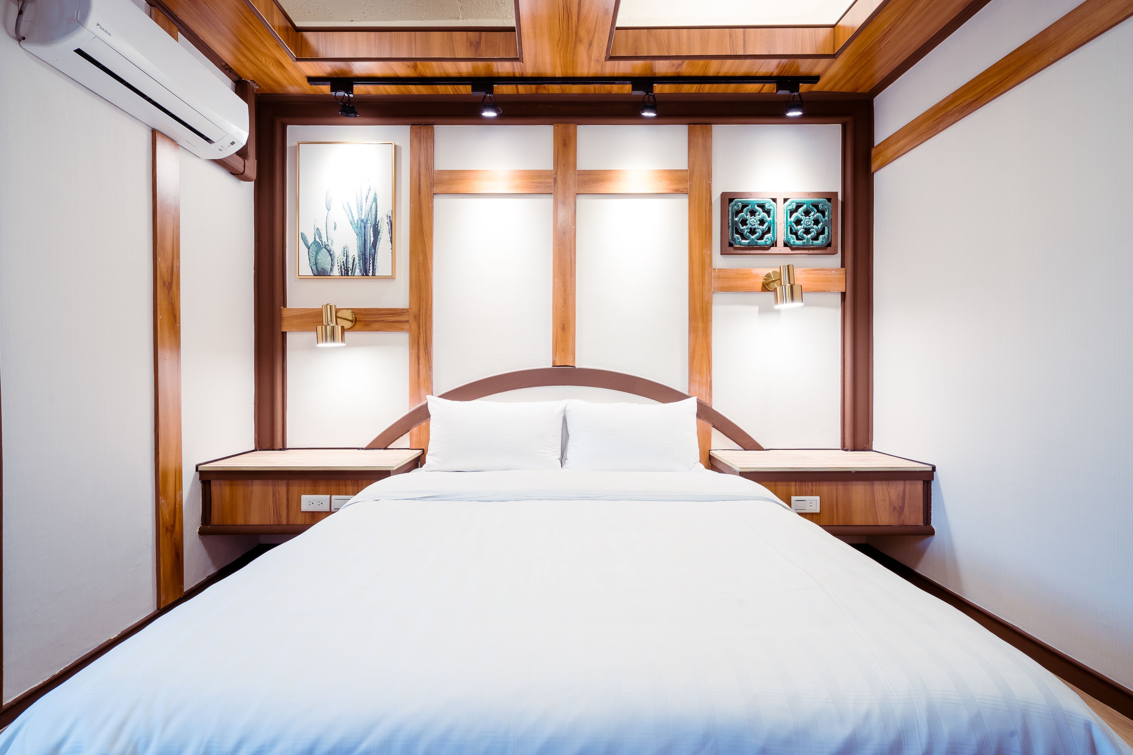 Un dormitorio ordenado con cabecera de madera, una cama con ropa de cama blanca y dos mesitas de noche.