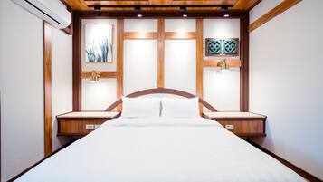Un dormitorio ordenado con cabecera de madera, una cama con ropa de cama blanca y dos mesitas de noche.