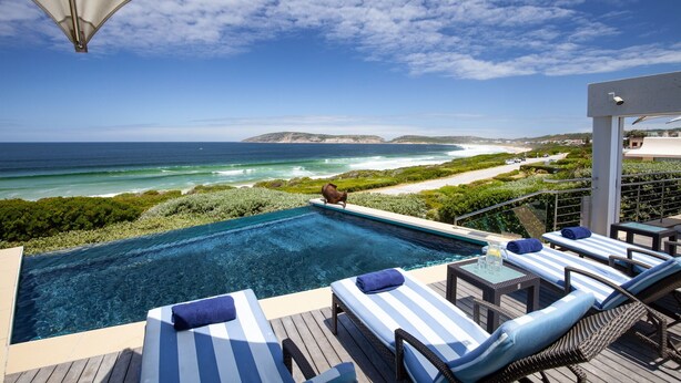 A poolside area with lounge chairs and a view of the ocean. - Periwinkle Guest Lodge (Plettenberg Bay)