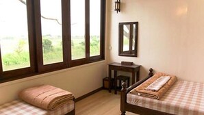 A room with two beds, a desk, and a window with a view of greenery. - YHA Bangkok Airport - Hostel (Bang Phli)