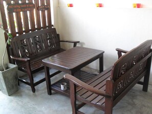 A wooden bench and table set against a white wall with a sign above the bench. - YHA Bangkok Airport - Hostel (Bang Phli)