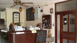 A reception desk with a sign for YHA Bangkok Airport, a menu board, and a Buddha statue. - YHA Bangkok Airport - Hostel (Bang Phli)