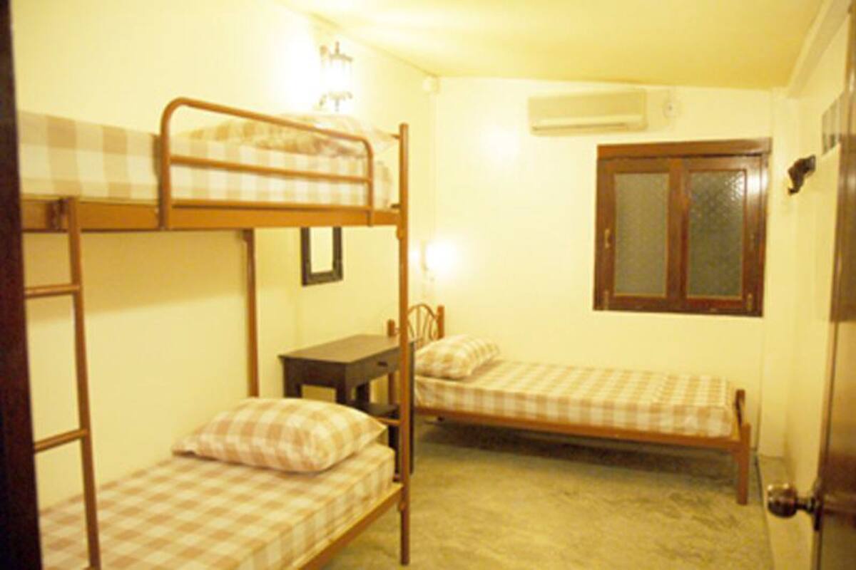 A dormitory room with bunk beds, a desk, and a window.