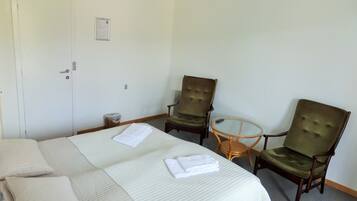 Hotelkamer met een bed, twee fauteuils, een klein rond tafeltje en een deur met een bericht op de muur.