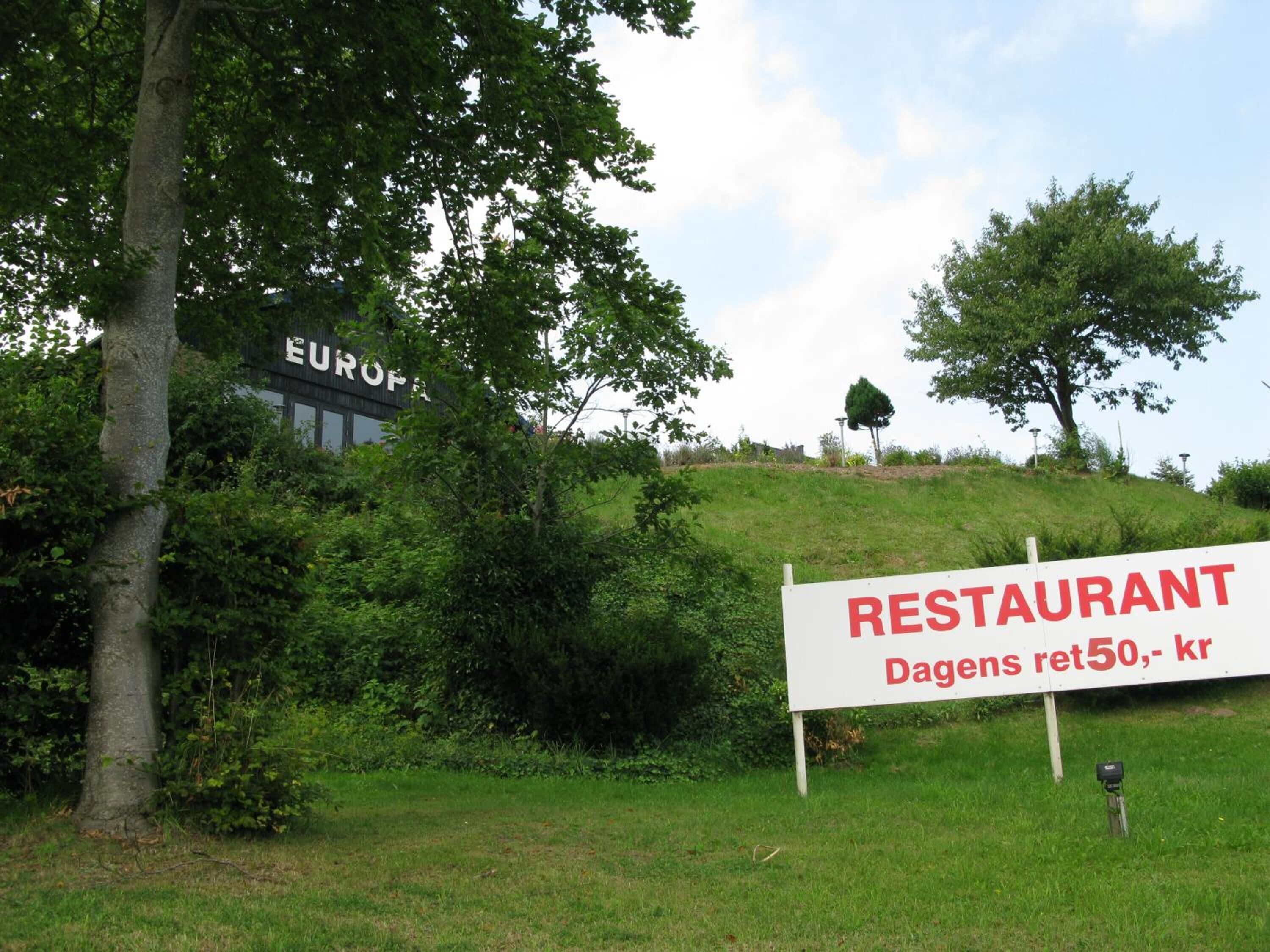 A sign for a restaurant with a partial view of a building labeled "EUROPA" in the background.