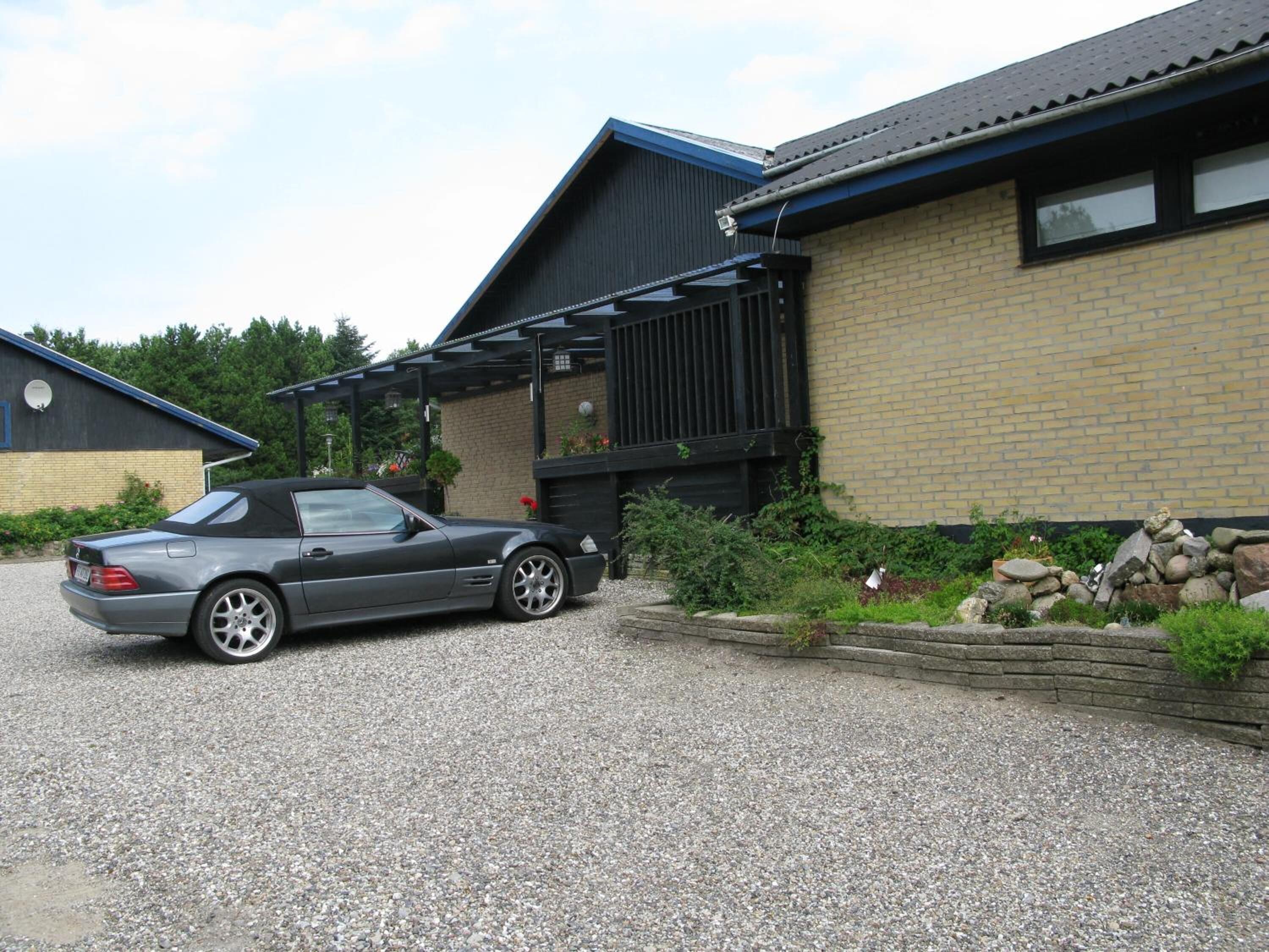 A grey convertible car parked in front of a building with a brick facade and a balcony.
