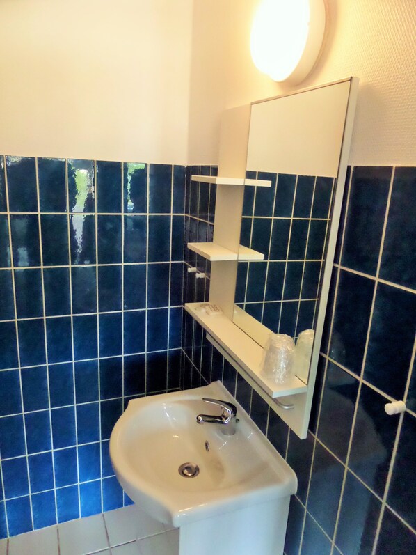 A bathroom with a white sink, a mirror, and blue-tiled walls.