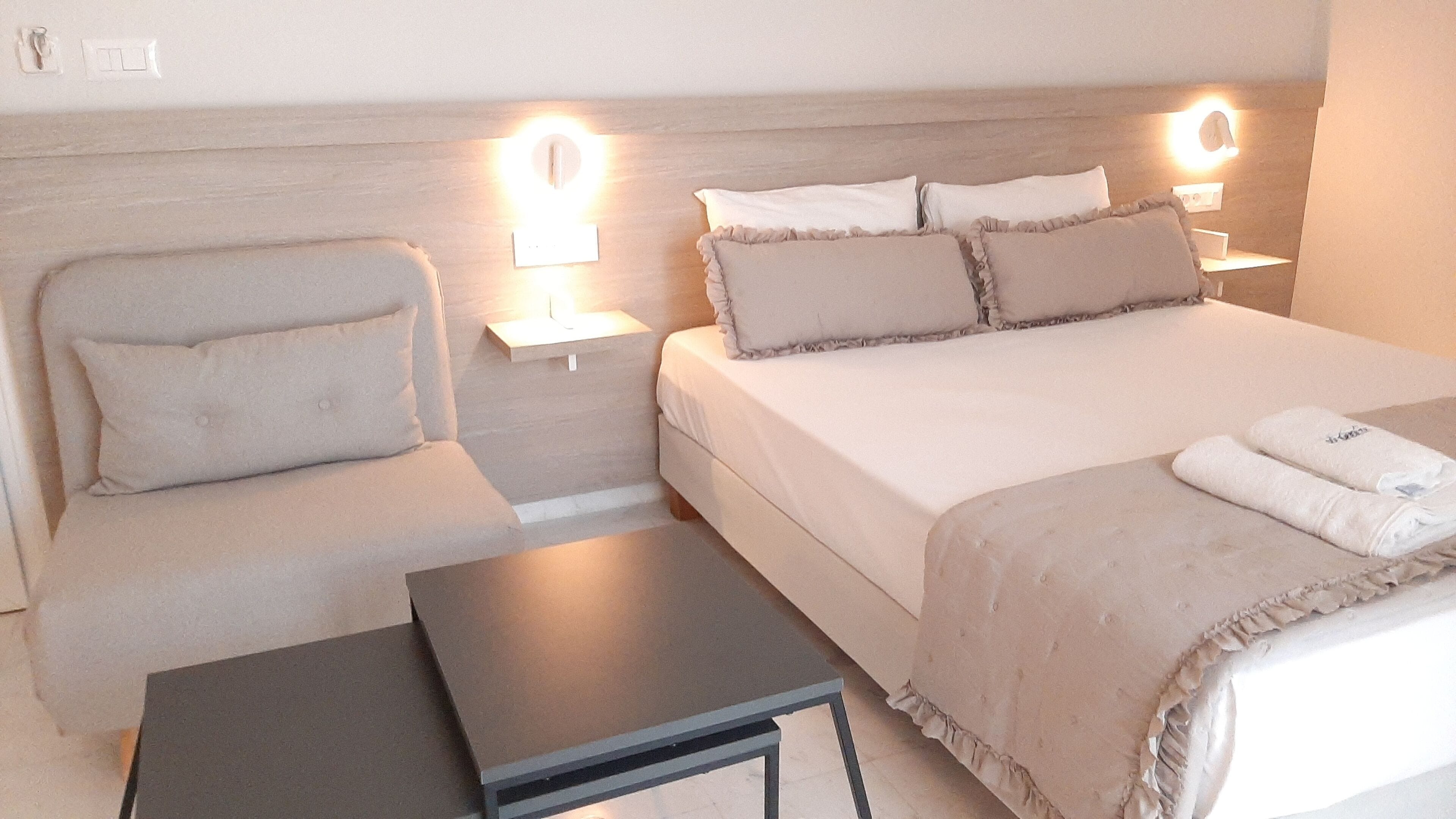 Ein Hotelzimmer mit einem Bett, einem Sessel, einem kleinen Tisch und Nachttischlampen.