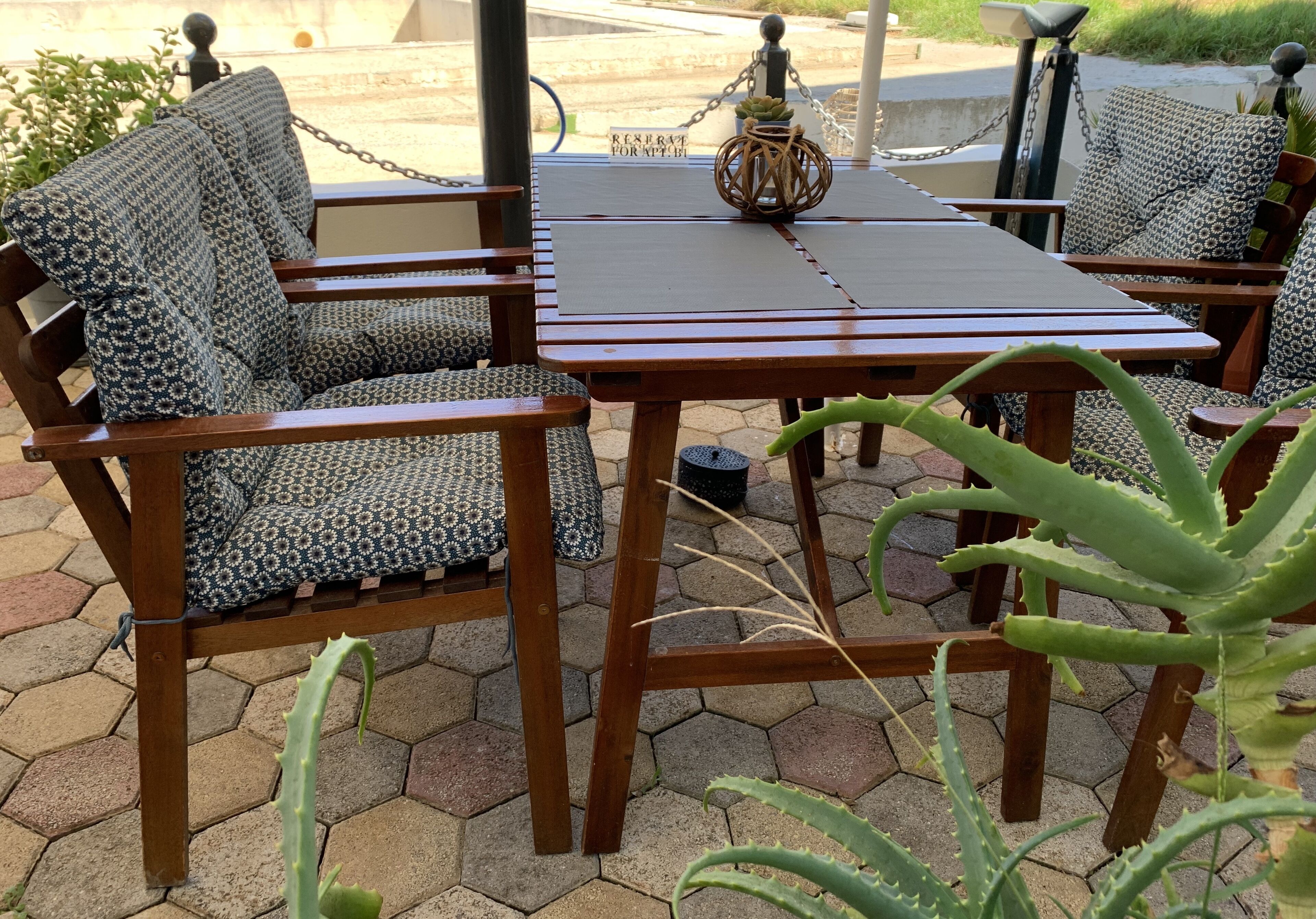 Una mesa de madera con cojines estampados y un jarrón decorativo.