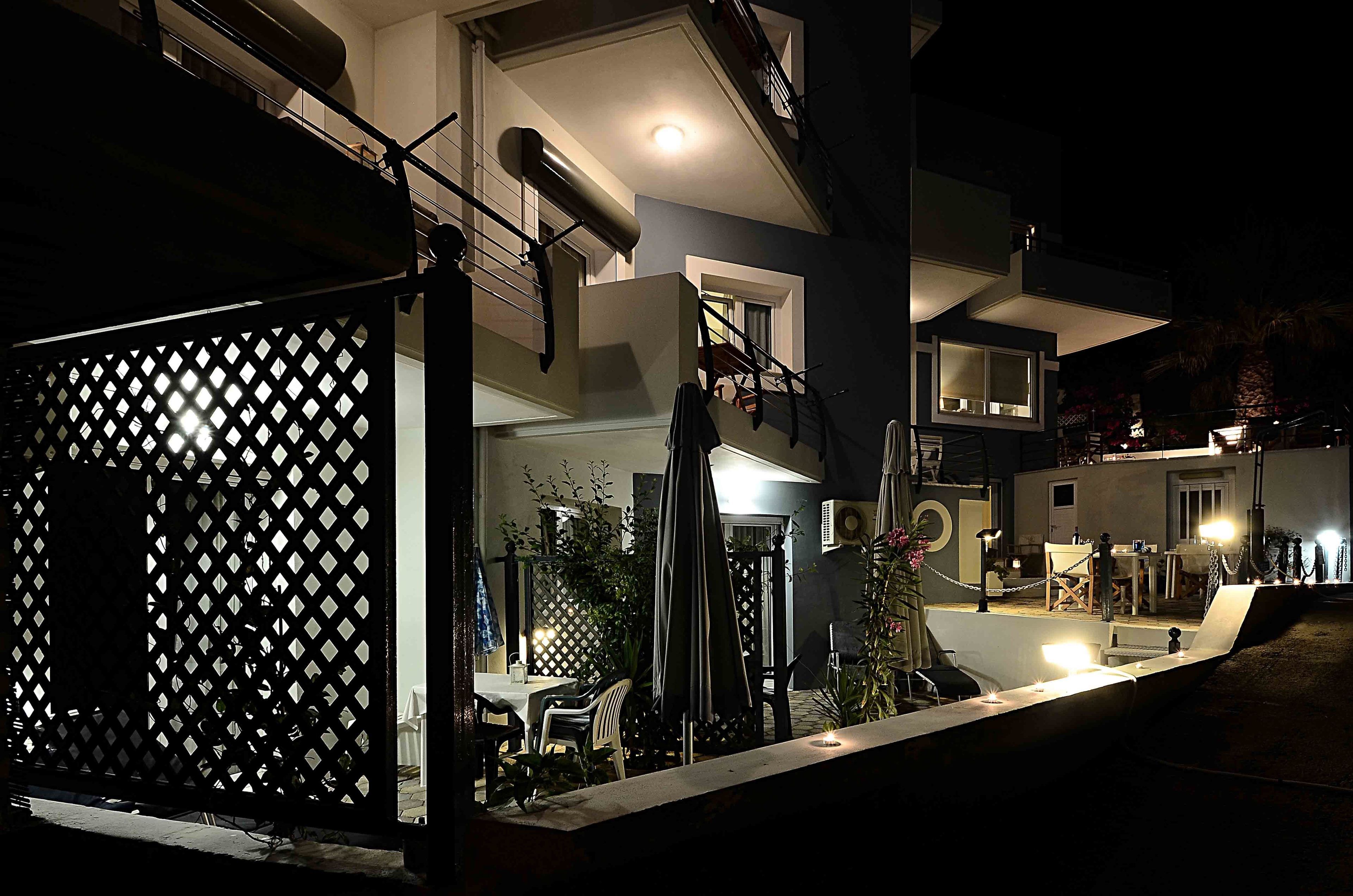 Et moderne hus med to etager, en balkon, udendørs siddeplads og en godt oplyst terrasse.