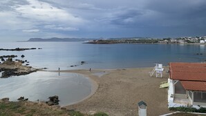 A beach with a clear view of the sea, a sandy shore, and a building with a red roof. - Sea Breeze (Chania)