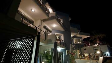 A modern multi-story building with a well-lit entrance and outdoor seating area.