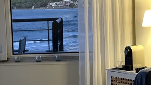 A room with a view of the sea, a glass table with a candle, and a lamp. - Sea Breeze (Chania)