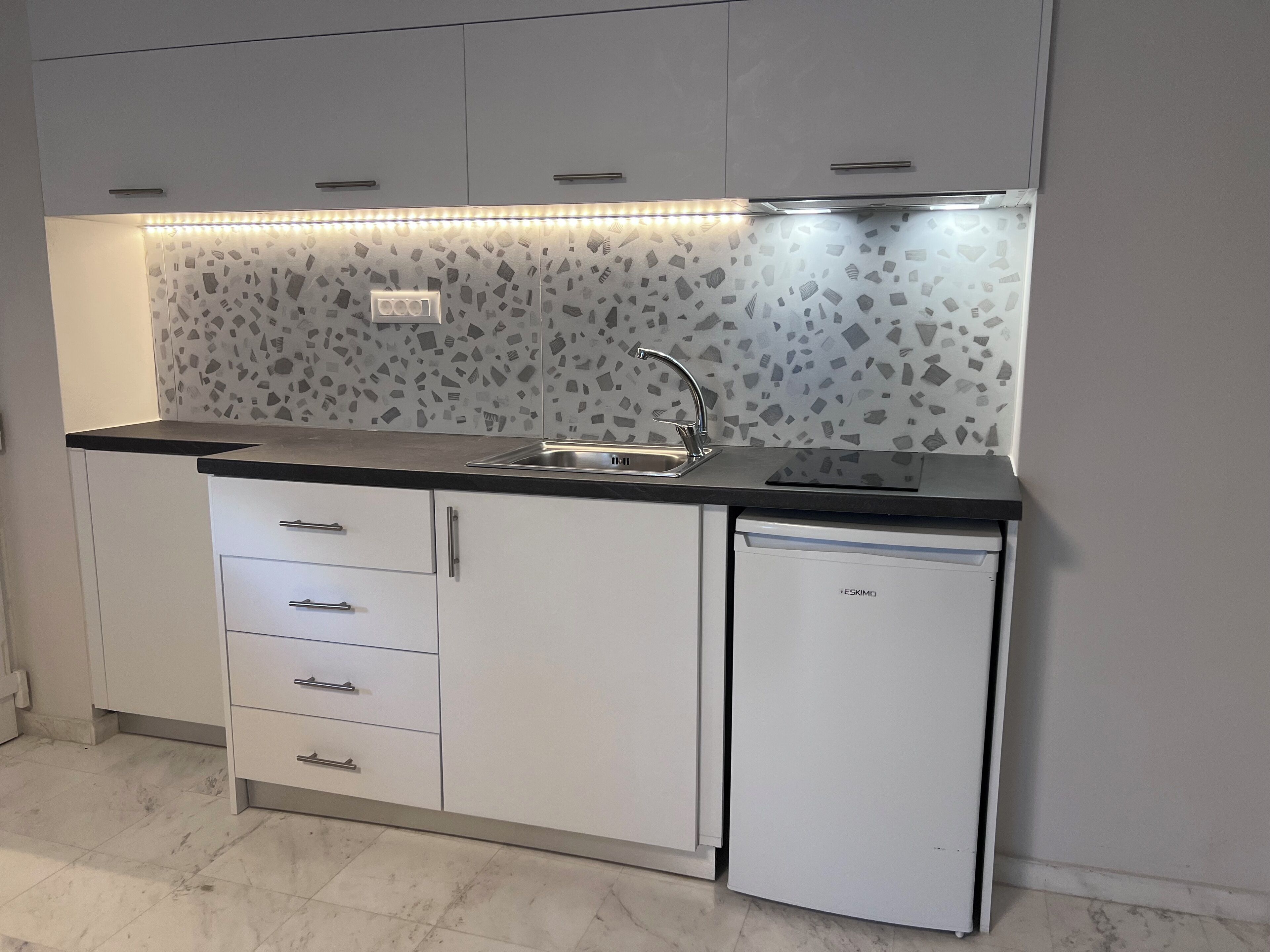 Een moderne keuken met een inbouwvaatwasser, een spoelbak en een spatwand met een mozaïektegel ontwerp.