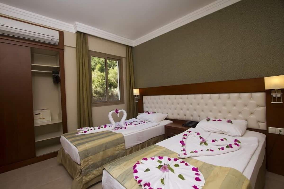 A hotel room with two beds, a wardrobe, and a window with curtains.
