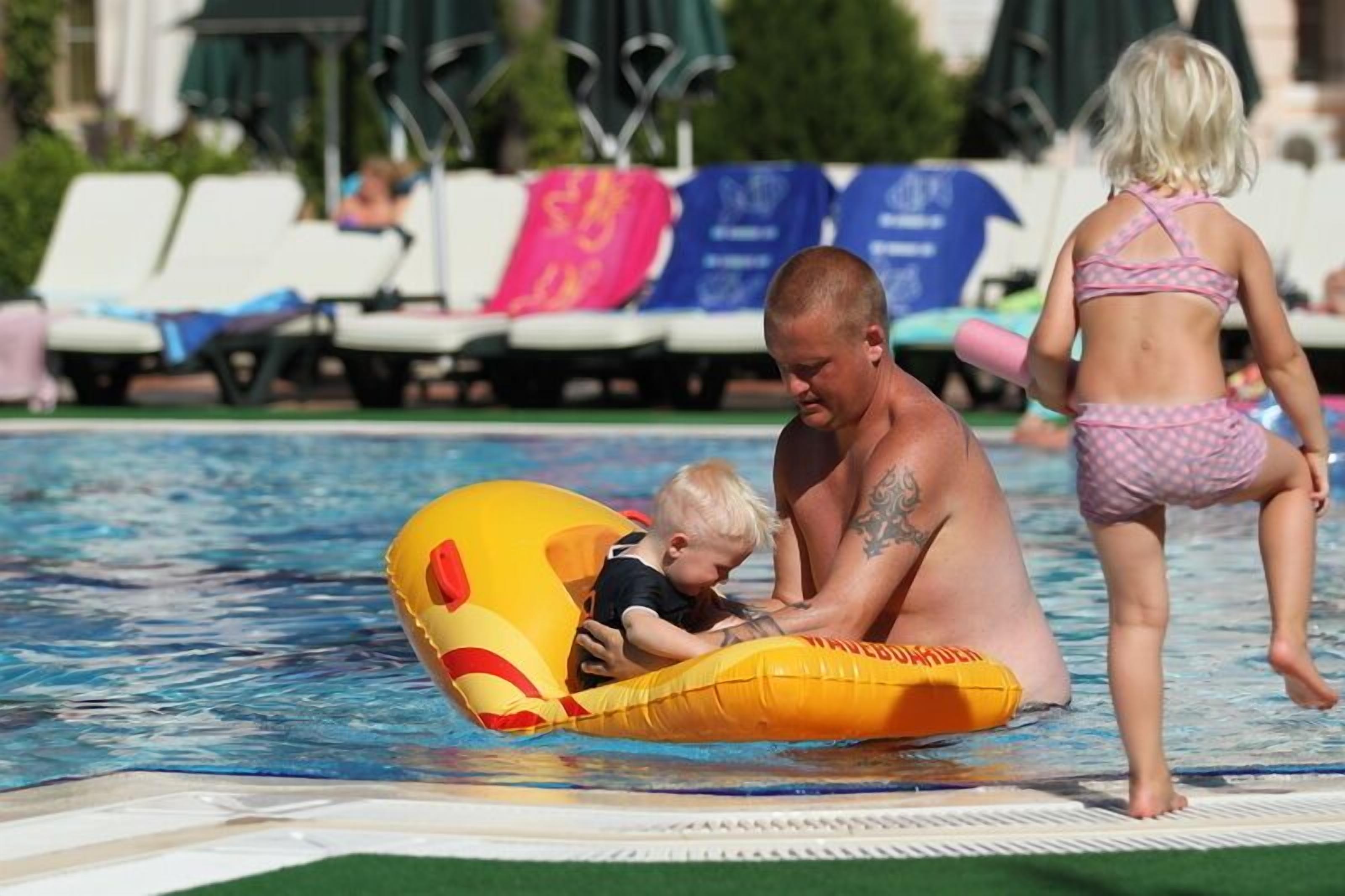 A pool area with lounge chairs and a person in a swimsuit.