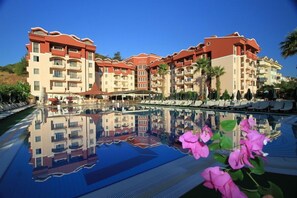 A hotel with multiple floors, balconies, and a pool area with lounge chairs. - Club Aida Apartments (Marmaris)