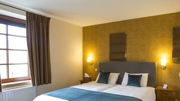 Una habitación de hotel con una cama grande, dos mesitas de noche, una ventana con cortinas y luces fijadas a la pared.