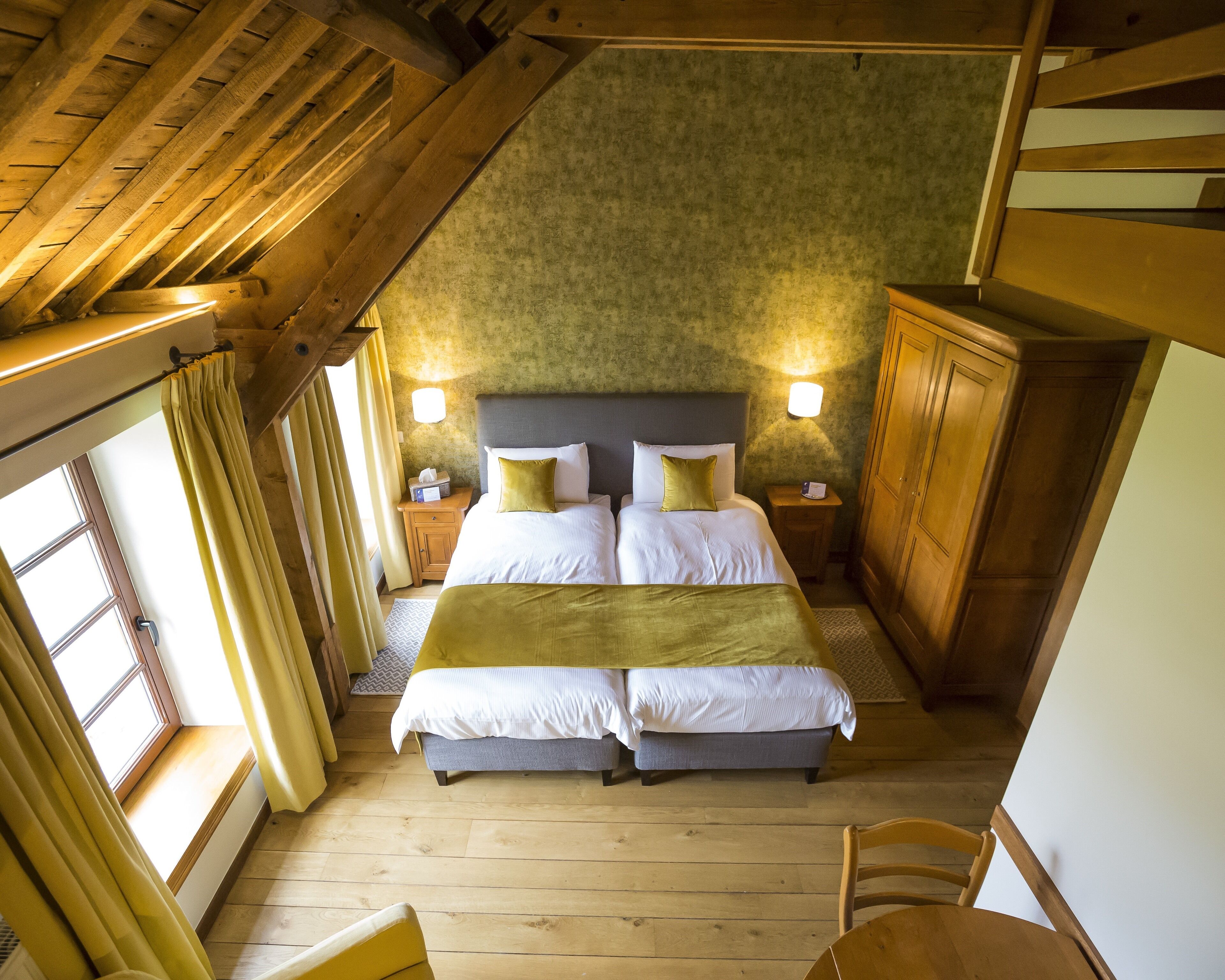 A bedroom with a large bed, two bedside tables, a wardrobe, and a window with curtains.
