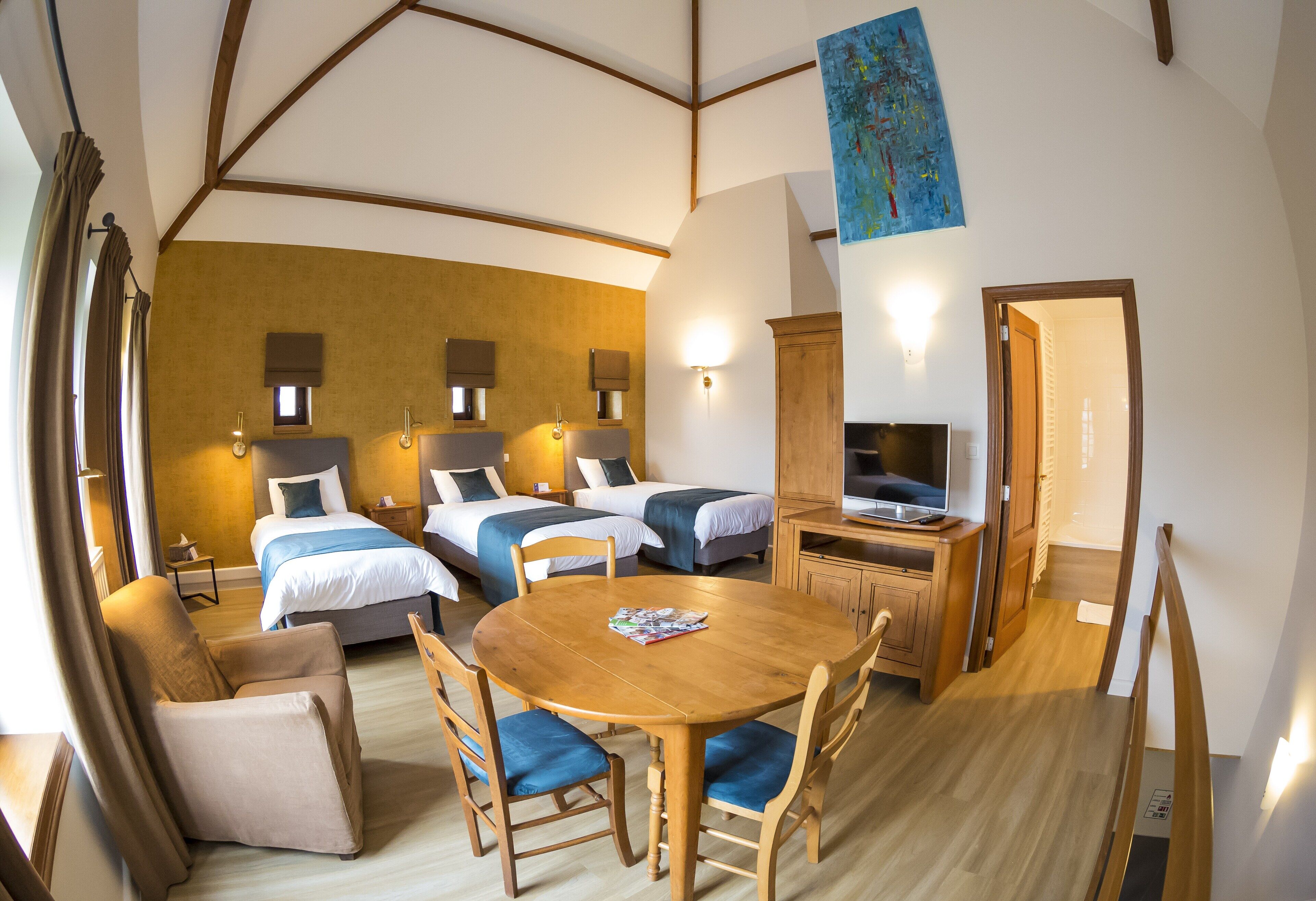 A hotel room with two beds, a wooden dining table, a TV, and a painting on the wall.