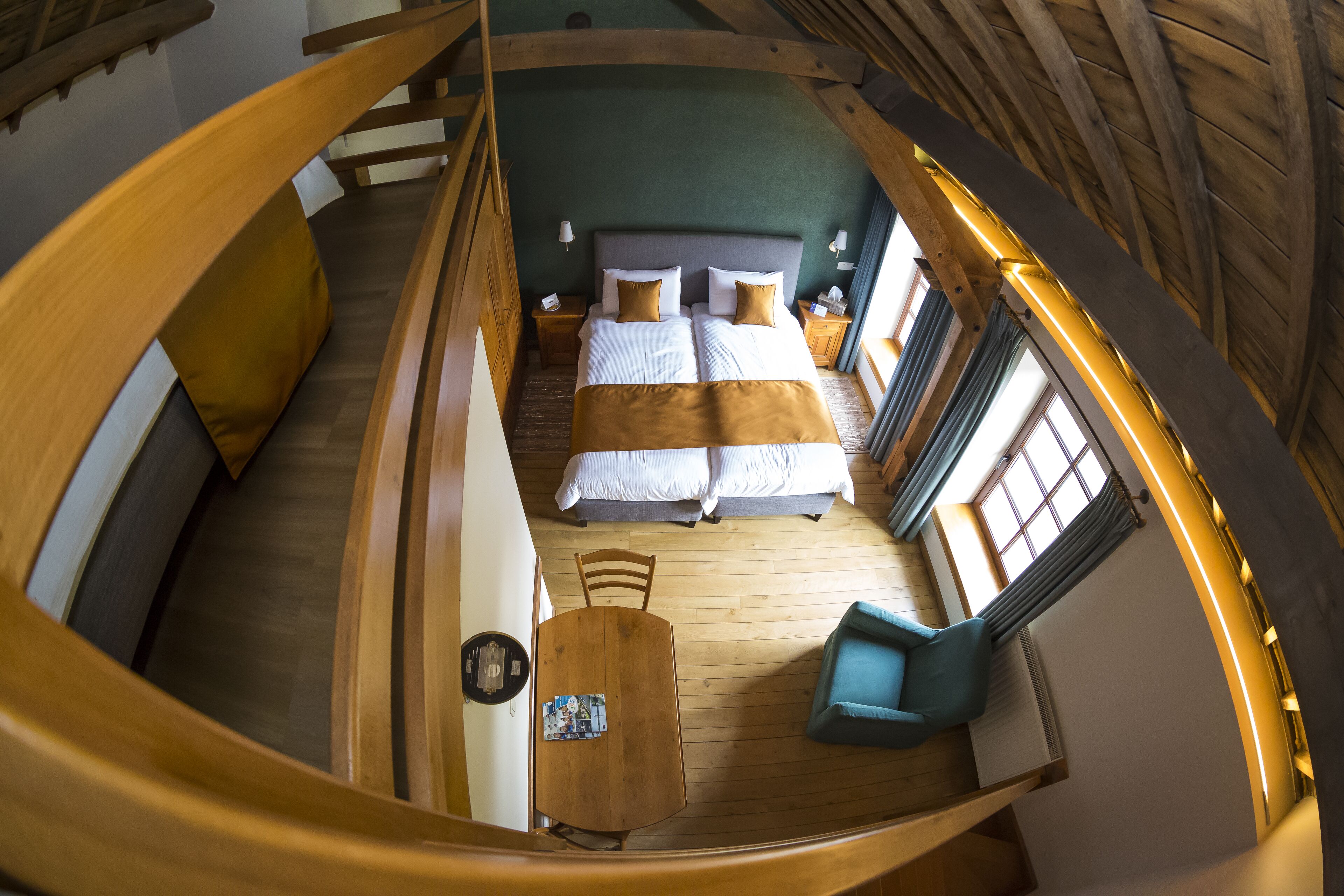 Una habitación circular con cama, dos mesitas de noche, una silla y una pequeña mesa.